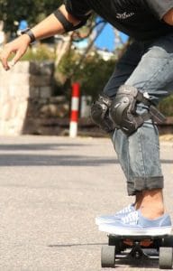 chico sobre longboard con rodilleras