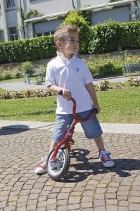 niño con bicicleta sin pedales frenado
