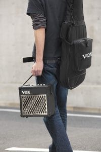 chico llevando un amplificador Vox